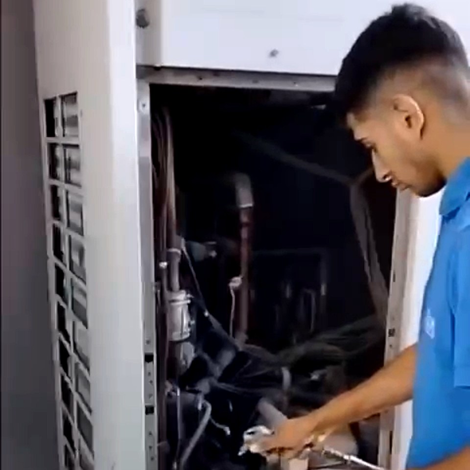Técnico trabajando dentro de un equipo de climatización central abierto